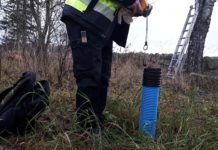 En person håller i ett måttband för att mäta i ett rör