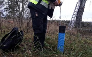 En person håller i ett måttband för att mäta i ett rör