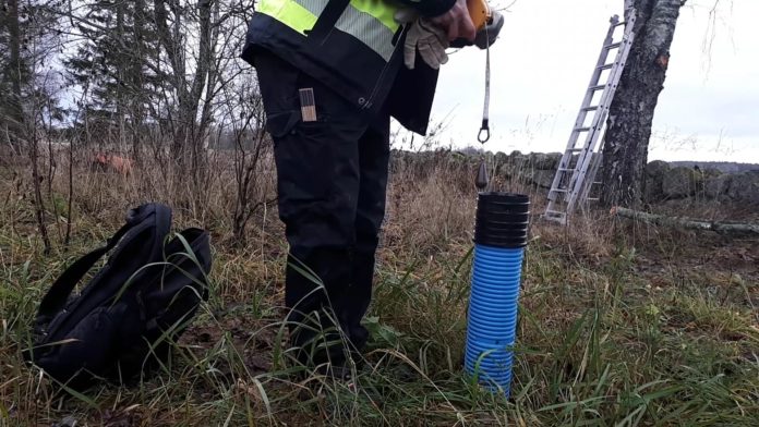 En person håller i ett måttband för att mäta i ett rör