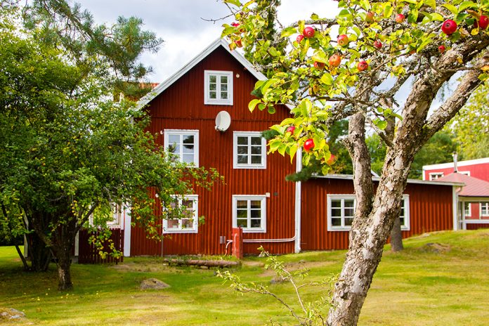 rött hus med vita knutar med fruktträd