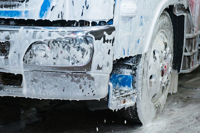Blå lastbilsfront full med tvätt-lödder vid tvätt.