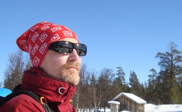 Man med skägg och solglasögon titta ut över snöigt landskap