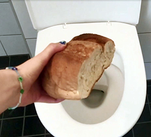 Brödlimpa som hålls över en toalett.