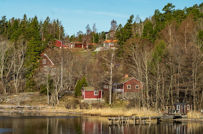 Röda stugor i sluttning ner mot vatten