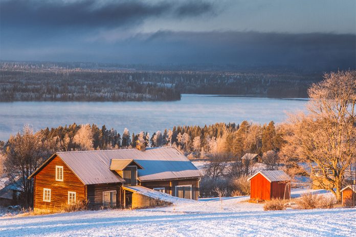 Brun lada i sluttning ner mot älv. Snö på marken.