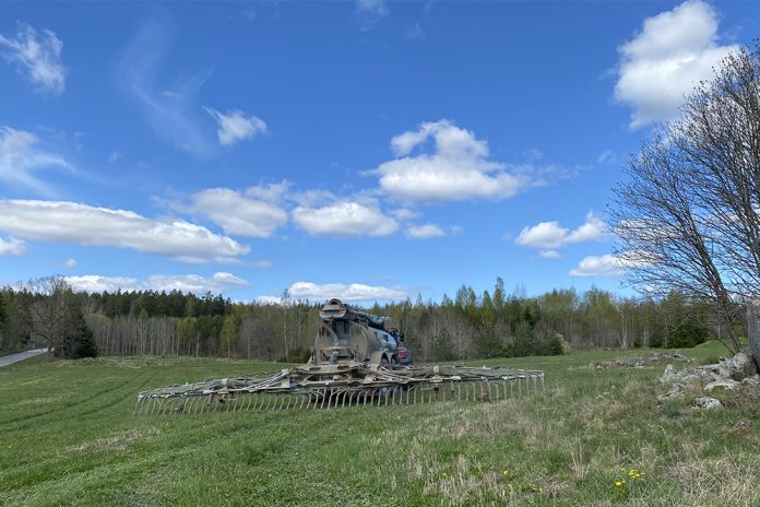 Flytgödselspridare med släpslangar kör på grönt fält