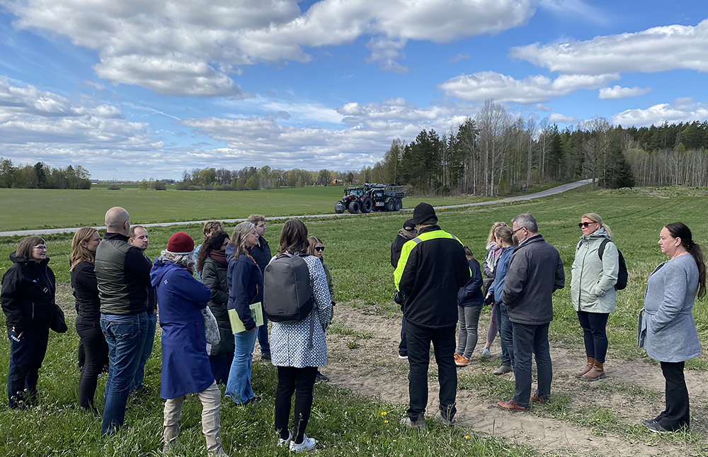 En grupp människor tittar mot en traktor på en väg.