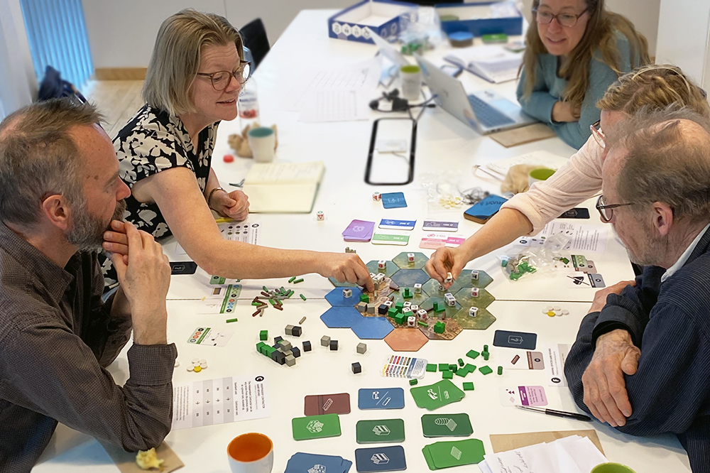 personer som spelar ett färgglatt brädspel runt ett vitt bord.