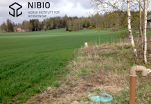 Grönt fält med en avloppsanläggning i åkerkanten, i förgrunden. NIBIO:s logotyp i övre vänstra hörnet.