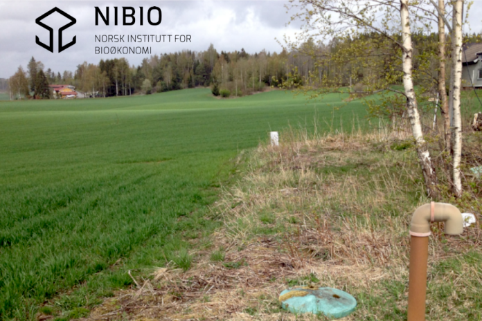 Grönt fält med en avloppsanläggning i åkerkanten, i förgrunden. NIBIO:s logotyp i övre vänstra hörnet.