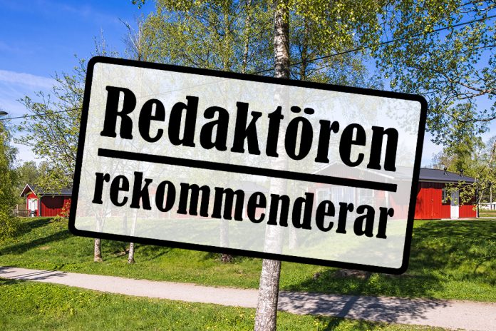 Skylt med texten redaktören rekommenderar. Bakom finns grönt gräs, en björk och röda stugor.
