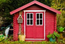 Liten röd stuga i trädgården.