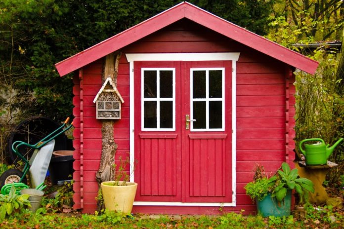 Liten röd stuga i trädgården.