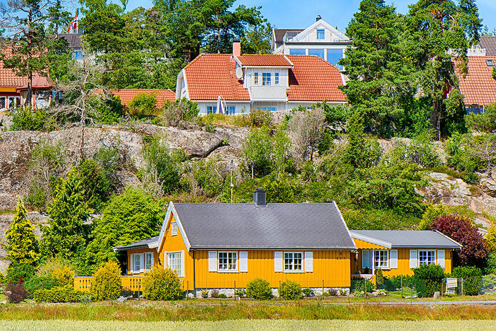 Gult trähus. Bakom finns en klippa och fler hus.